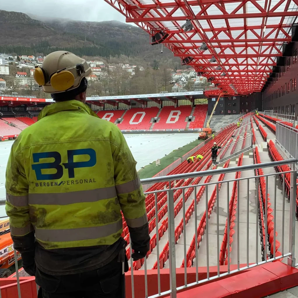 Byggearbeidere som arbeider på stadion med sikkerhetsutstyr og høyhastighetsverktøy under konstruksjon av idrettsanlegg.