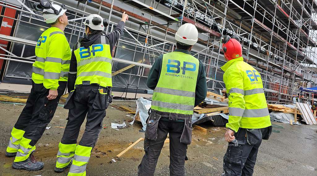 Sikkerhetsarbeidere på byggplass iført høye synlige vester med Bergen Personal logo, som gir sikkerhet og oversikt under bygge- og anleggsprosjekter.
